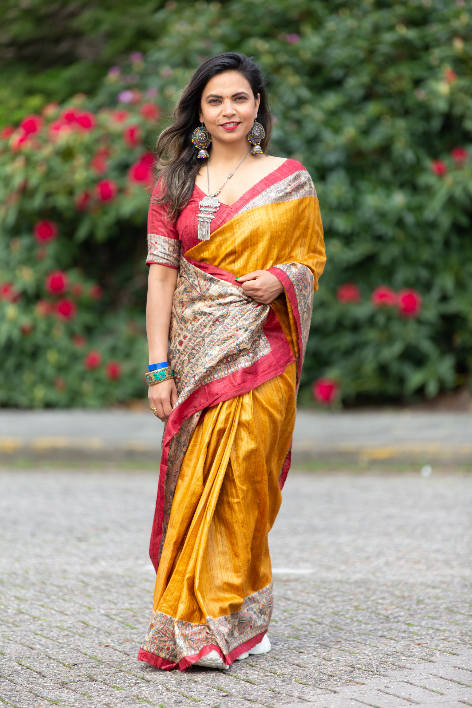 Aditi standing in a golden silk saree with silver tribal jewellery